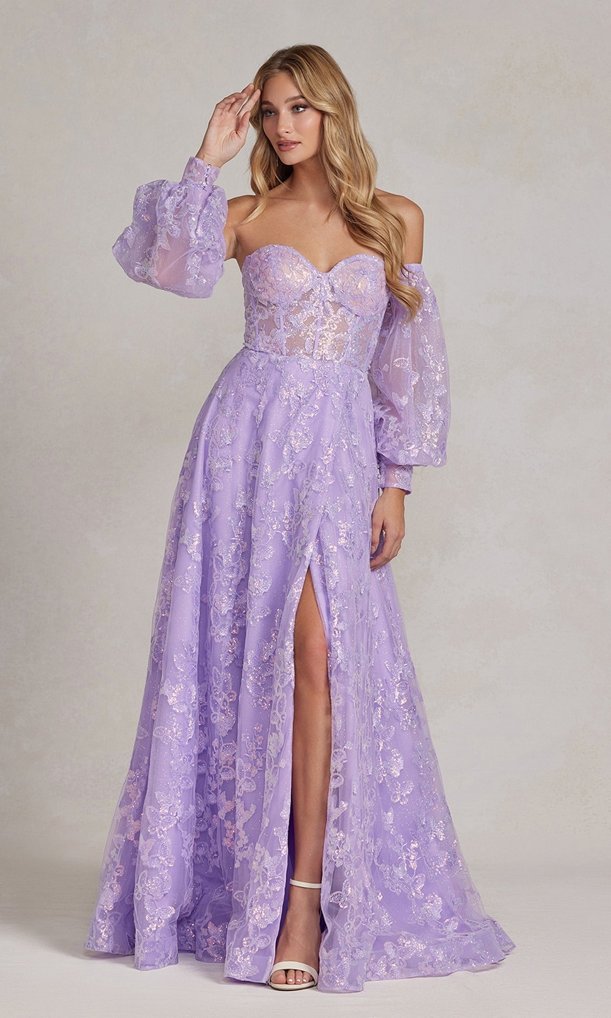 A woman stands against a light neutral background wearing the Long Puff-Sleeve Prom Dress with Sheer Bodice, featuring removable sheer long sleeves, lace accents, and a thigh-high slit in elegant lavender.